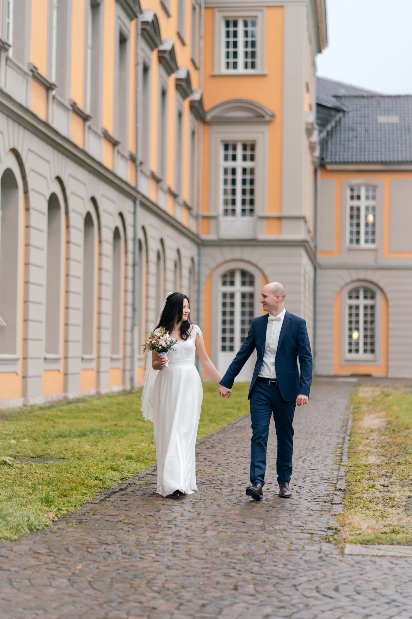 Brautpaar läuft glücklich durch Garten der Uni Bonn