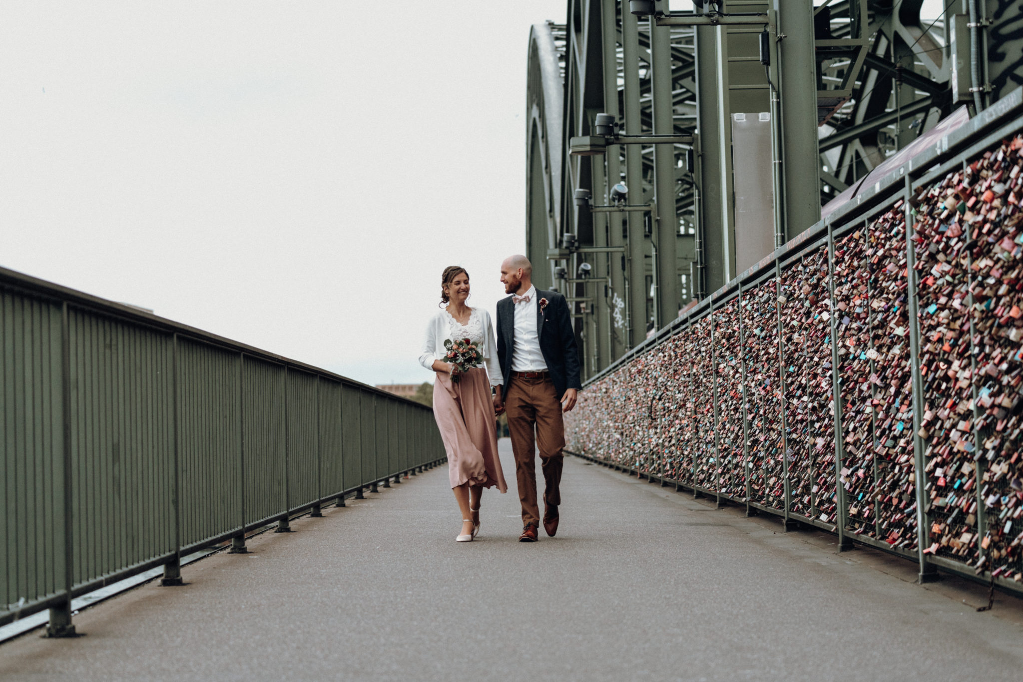 Glückliches Hochzeitspaar läuft auf Hohenzollernbrücke in Köln