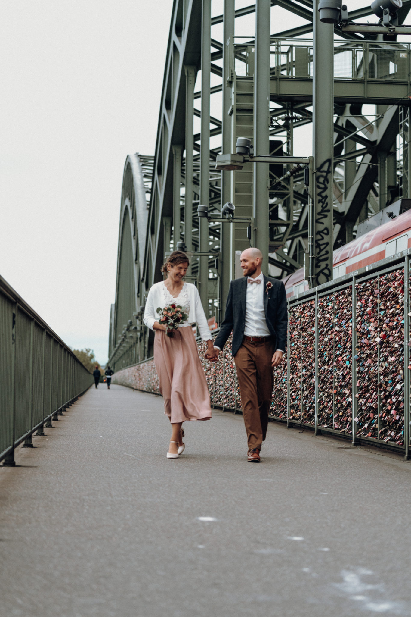 Paar läuft glücklich auf Hohenzollernbrücke in Köln