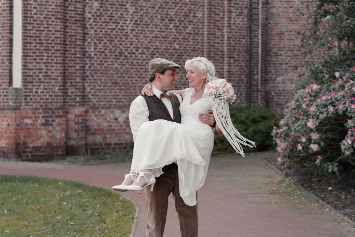 Bräutigam hebt seine Braut vor Kirche in Landesgartenschau Kamp-Lintford