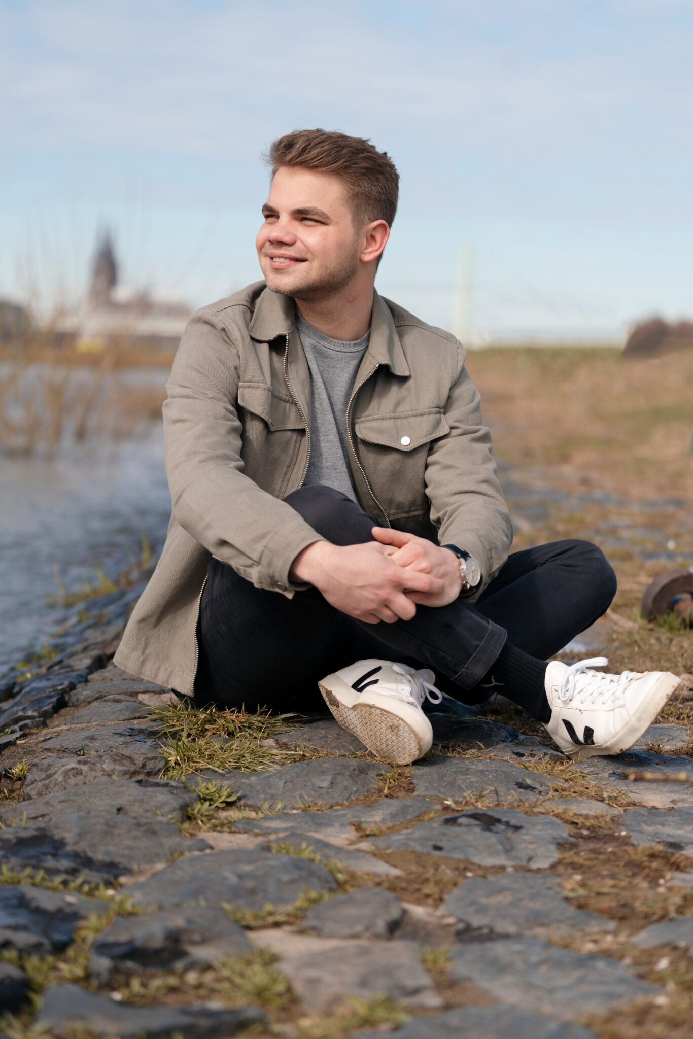 Outdoor Tinder Fotoshooting von jungem mann der am Fluss sitzt 