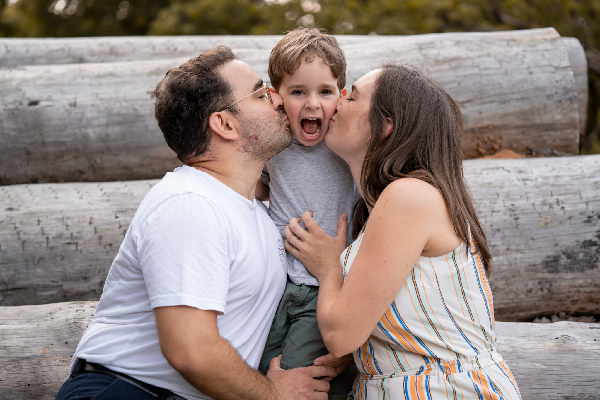Vater und Mutter küssen ihren Sohn auf die Wange Familienshooting