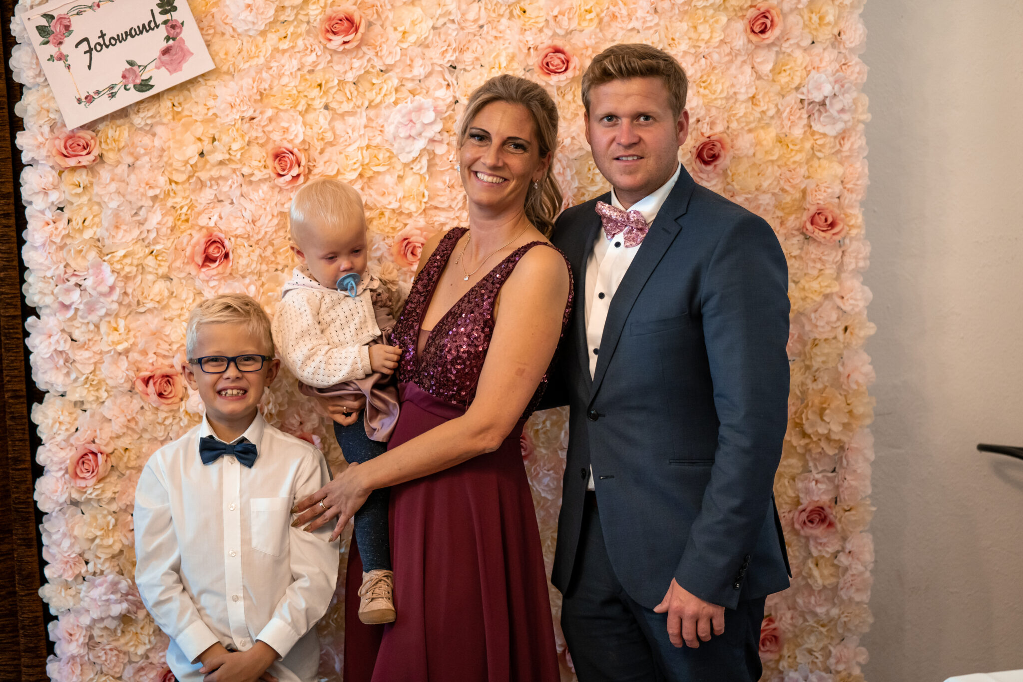 Familienfoto vor Fotowand in Hochzeitslocation