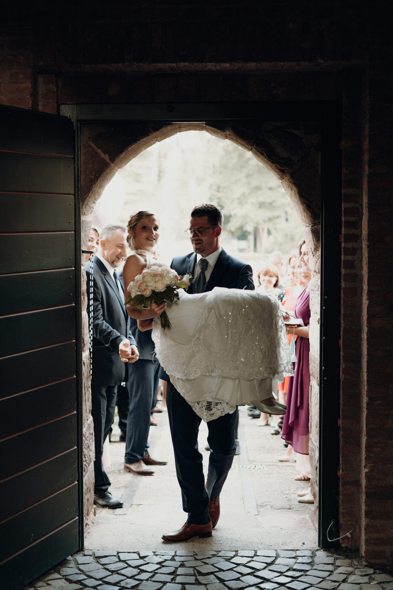 Bräutigam trägt seine Frau durch den Eingang