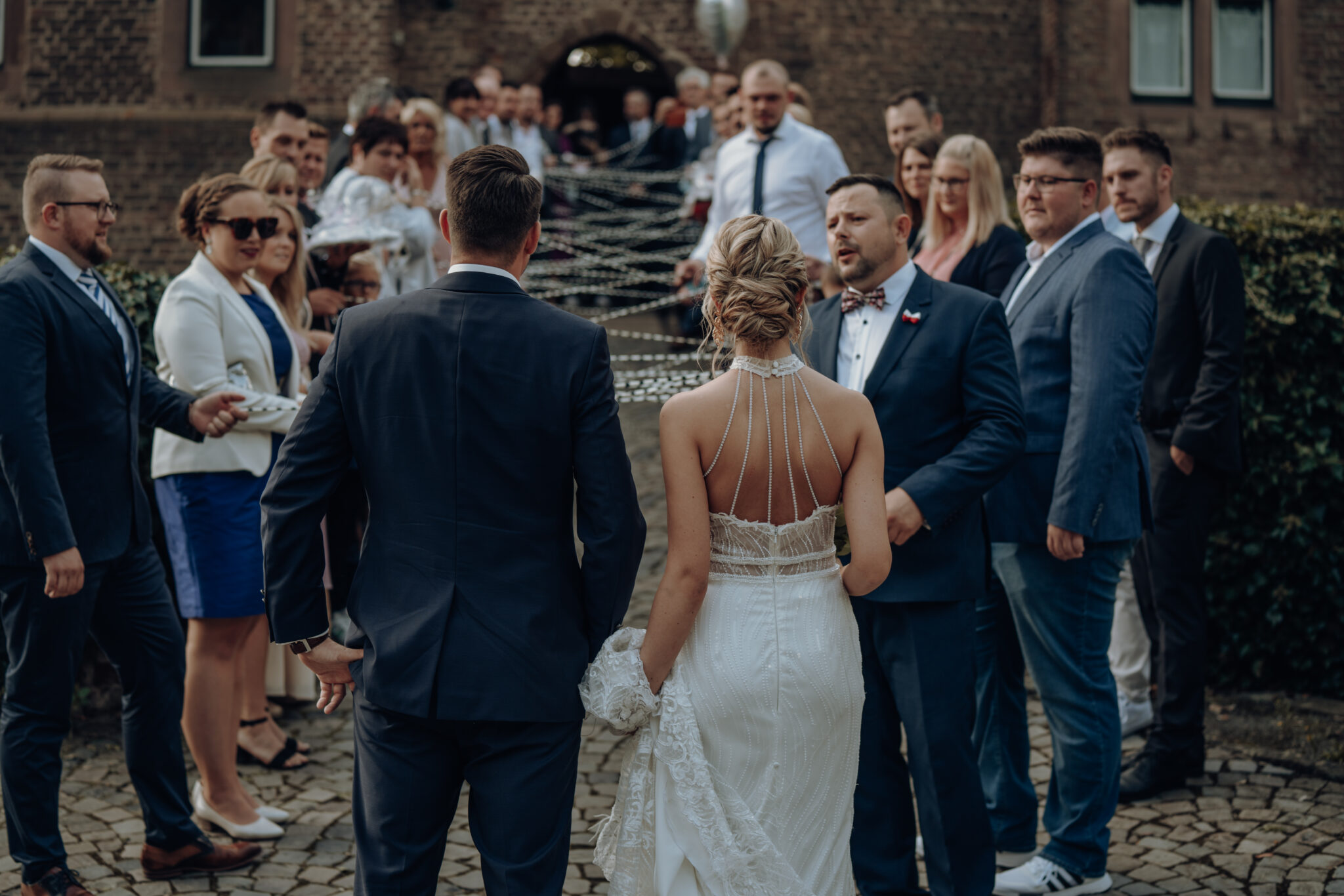 Brautpaar geht durch Spalier in die Hochzeitslocation der Burg Konradsheim