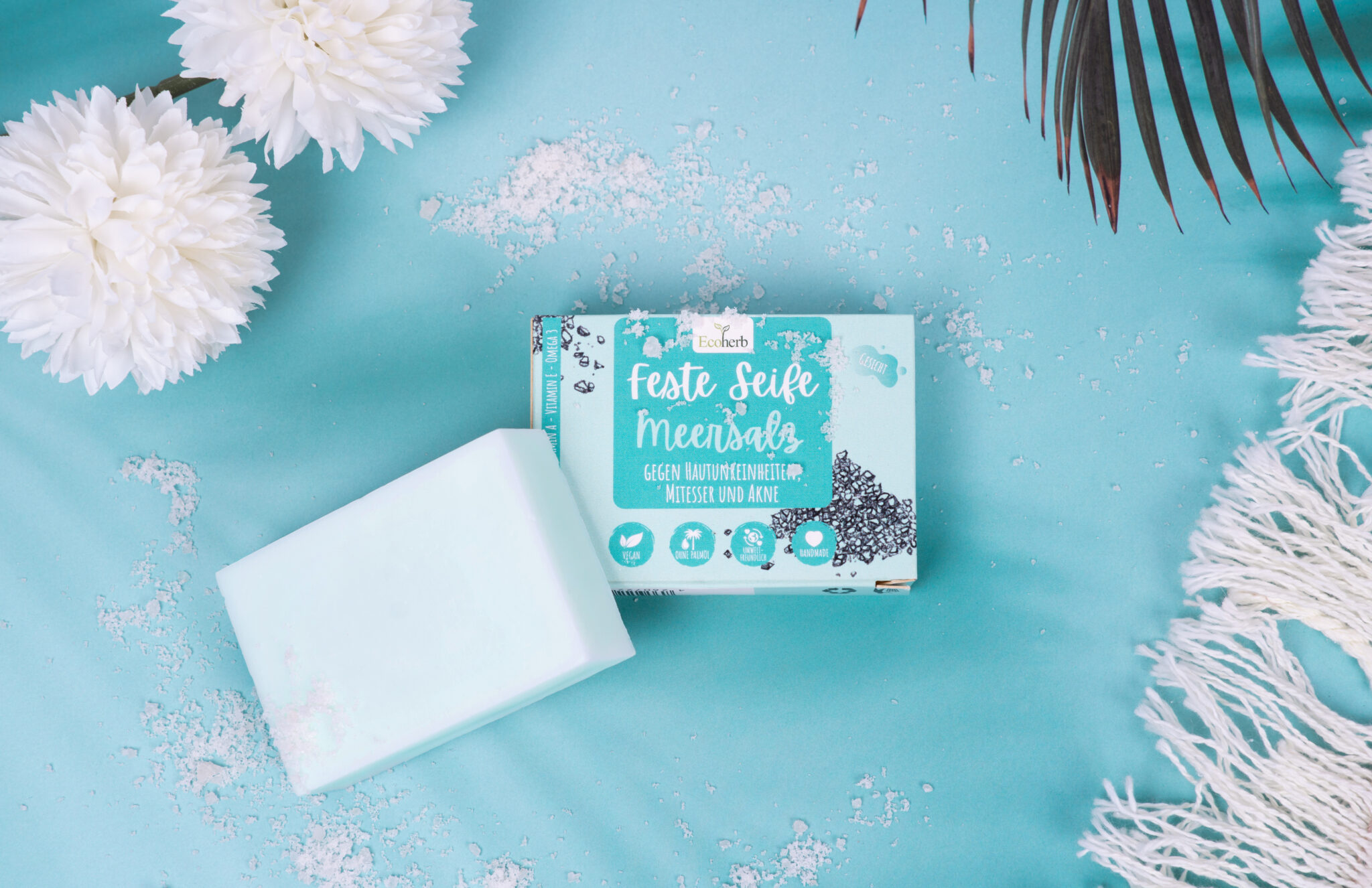 Produktfotografie, Verpackung von Fester Seife mit Meersakz von Ecoherb auf Türkise Untergrund mit Blumen und Teppich