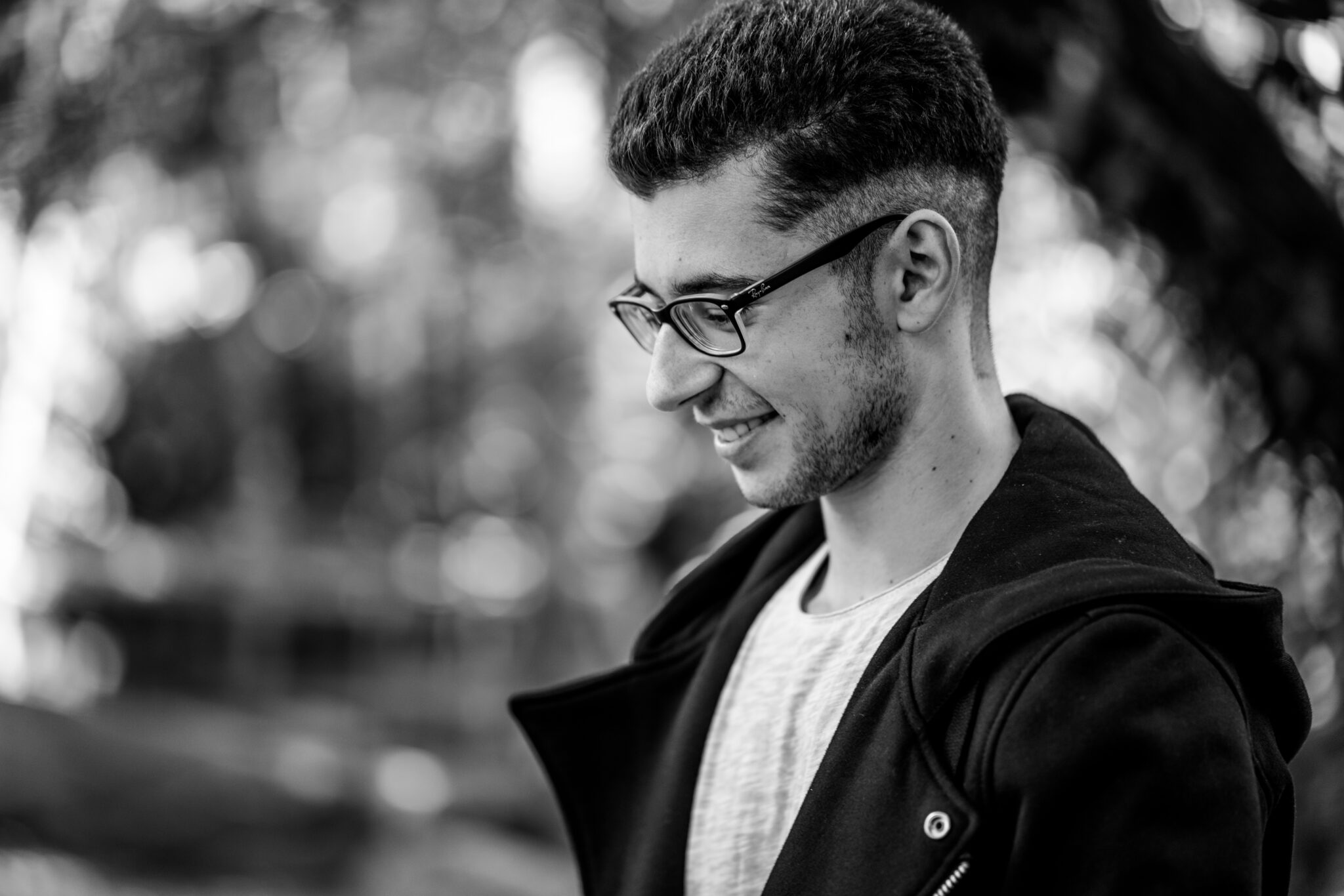 Seitliches Portrait von jungem Mann mit Brille in Schwarz Weiß