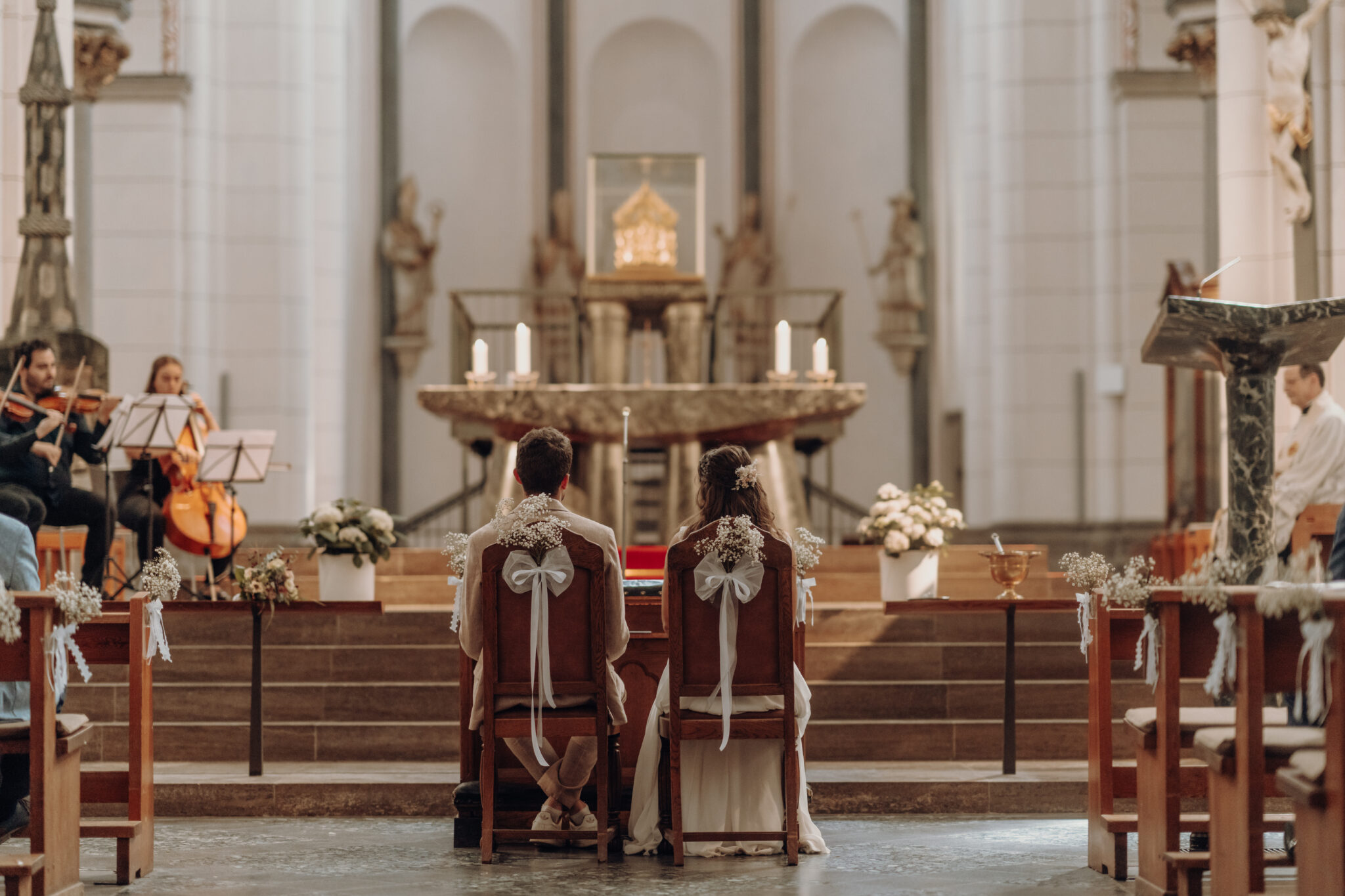Brautpaar sitzt an Alter während kirchlicher Trauung 