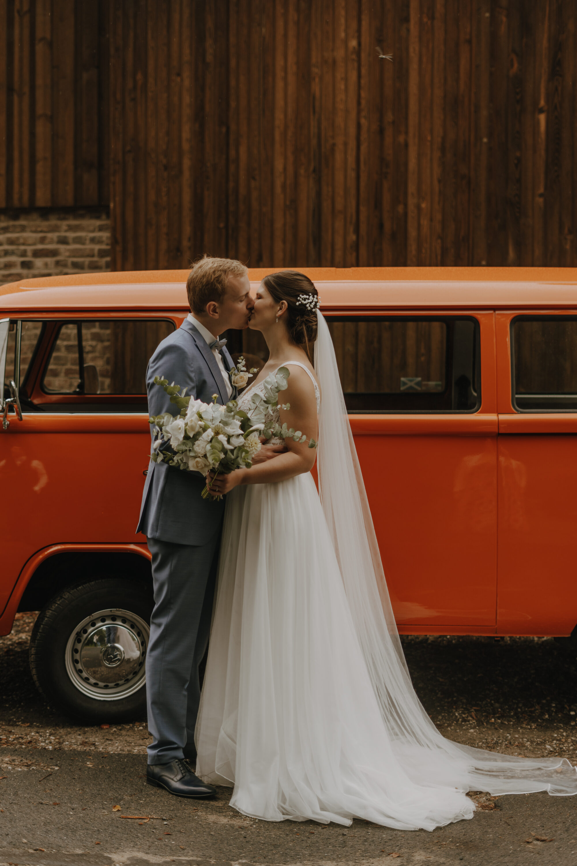 Kuss bei Hochzeitsfotoshooting vor dem Hochzeitsauto 