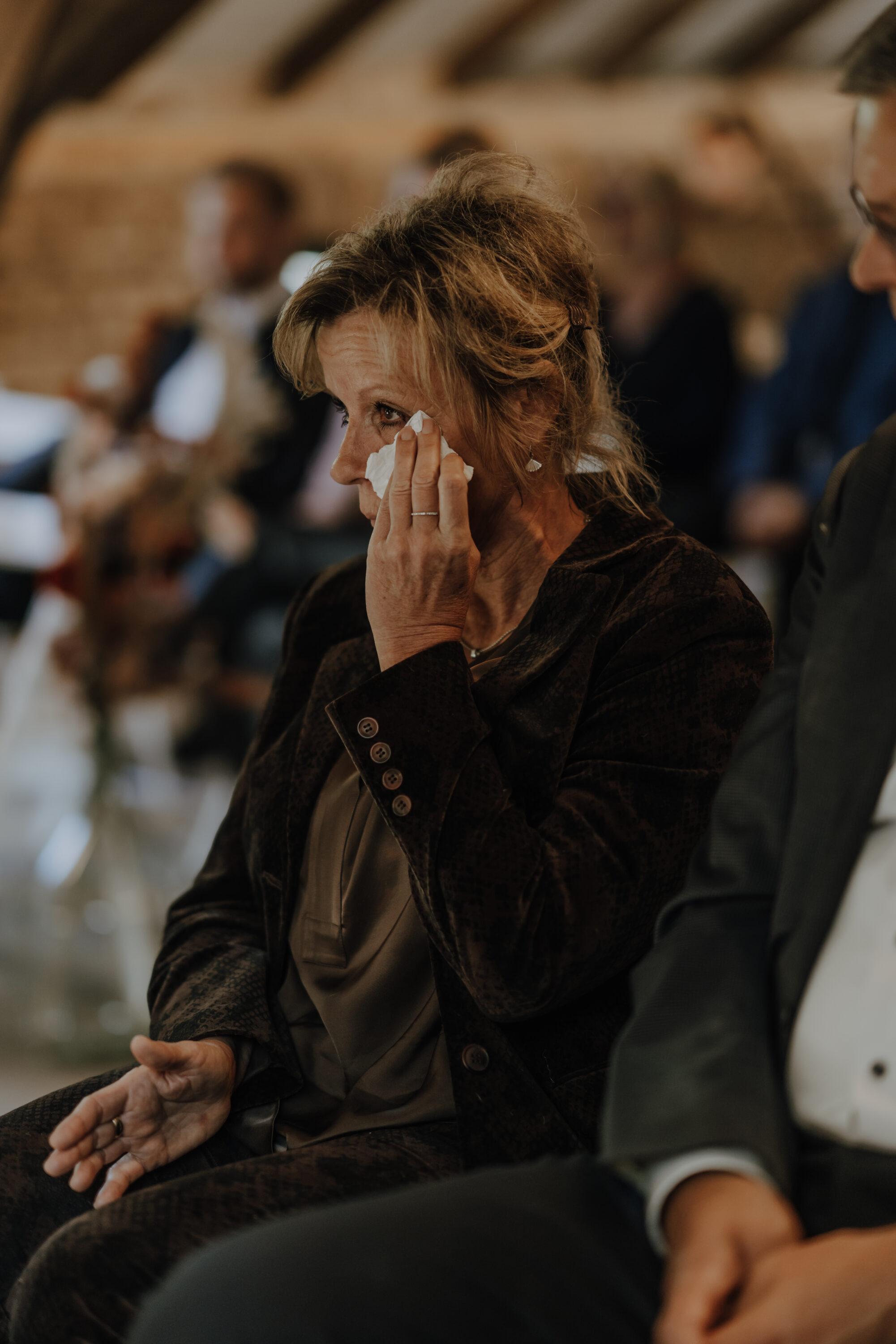 Weinender weiblicher Gast wischt sich gerührt Tränen mit Taschentuch weg