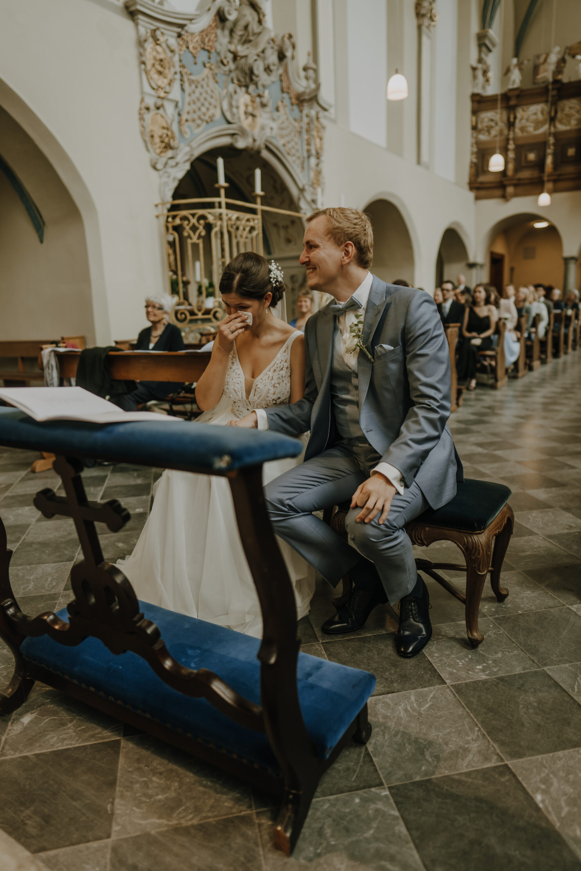 Freudentränen bei Braut, Bräutigam lächelt, sitzen am Altar