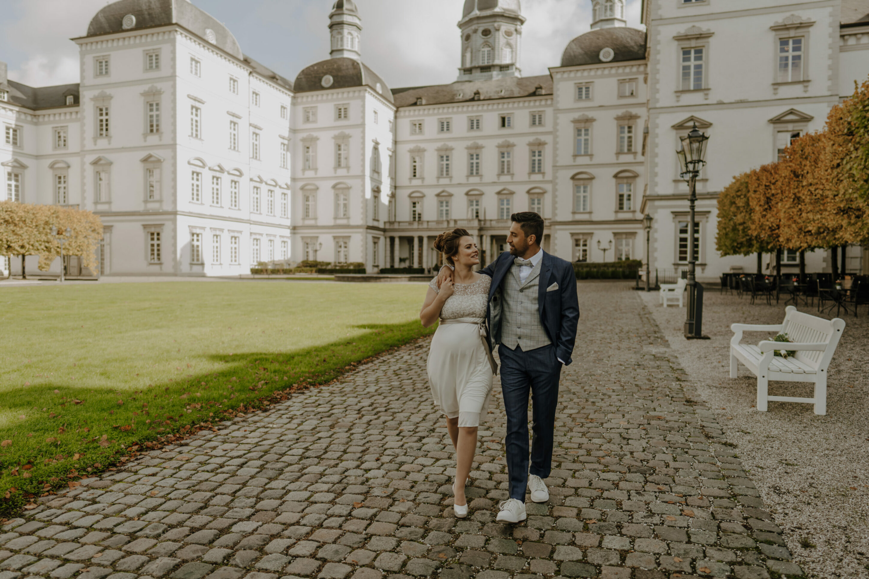 Hochzeitspaar gemeinsamer Spaziergang durch Schlosspark, schauen einander an