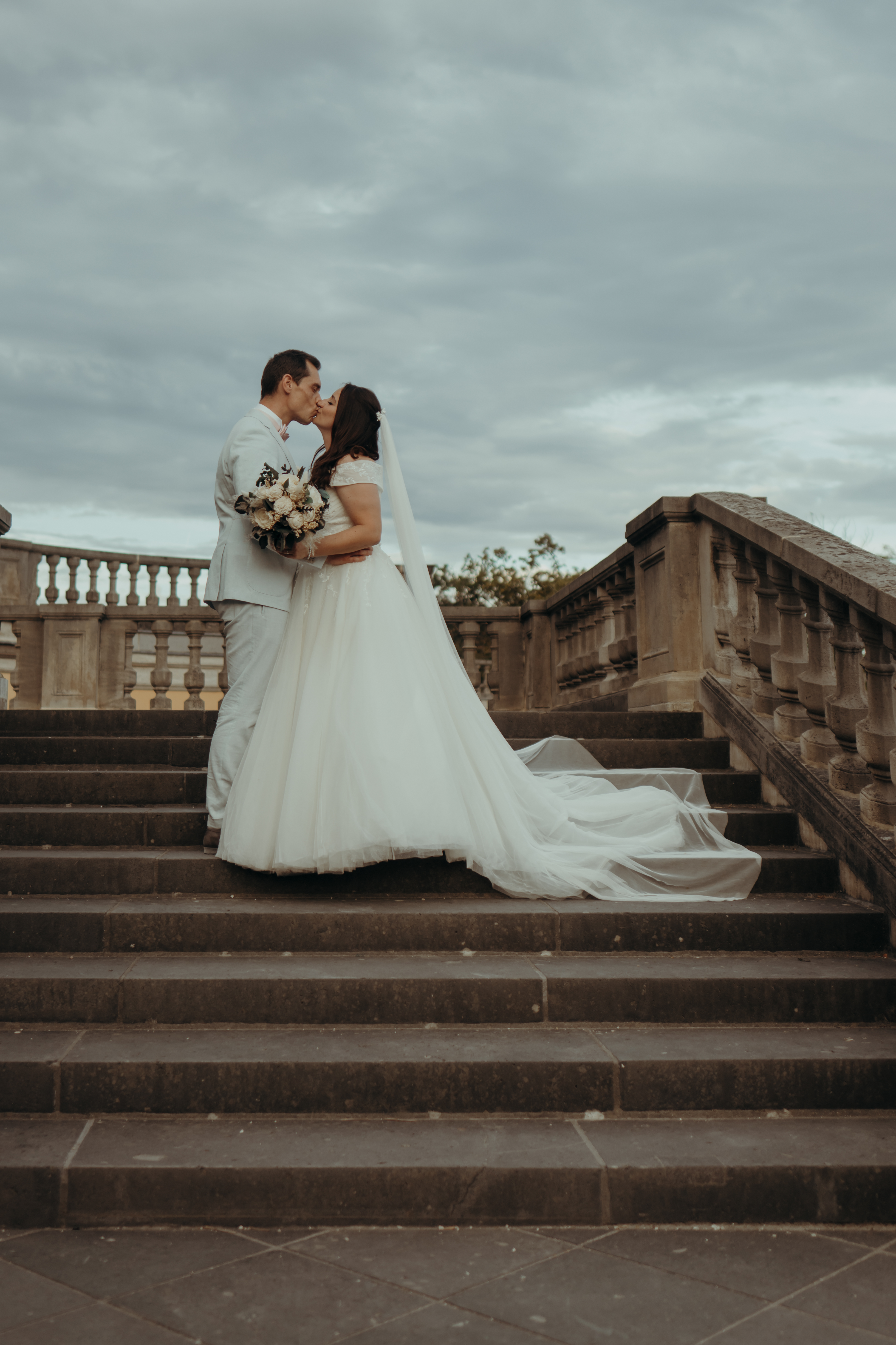 Brautpaar sich küssend auf Schlosstreppe, seitlich