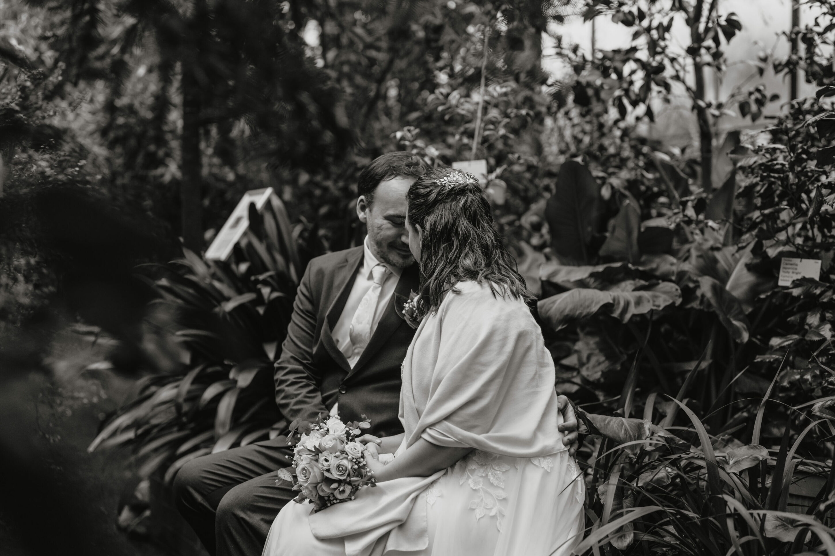 Botanischer Garten Köln: Brautpaar sitzt auf Mäuerchen Stirn an Stirn, schwarz weiß