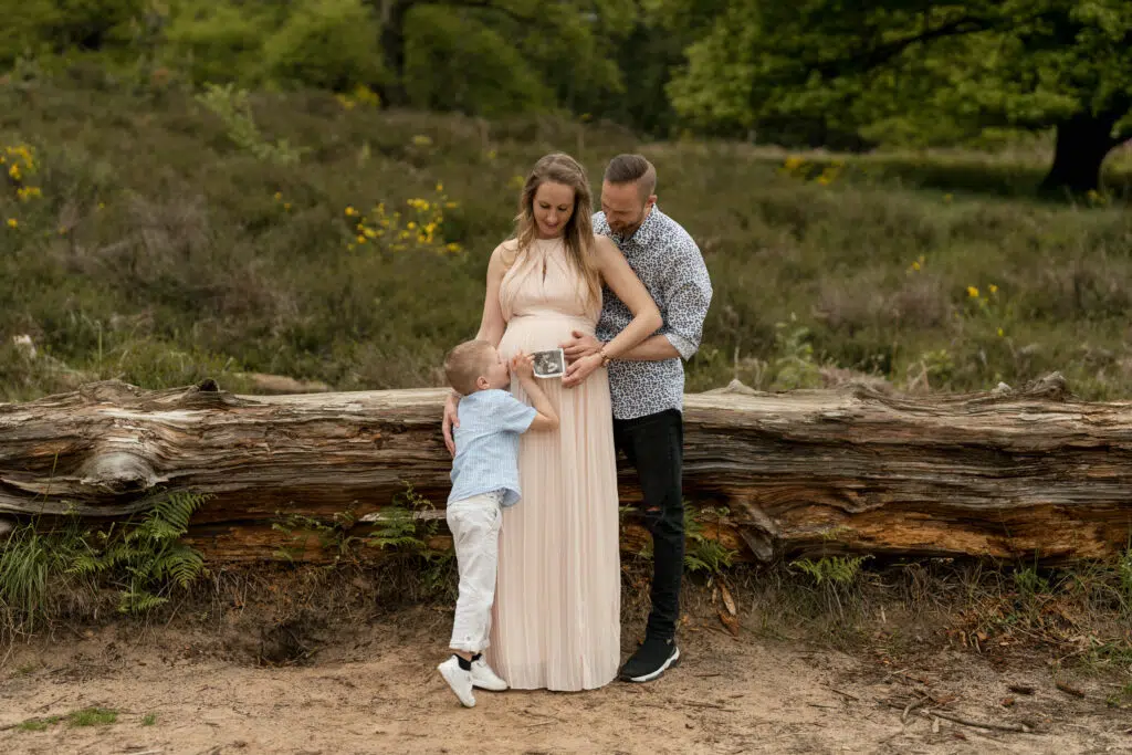 Babybauch Fotografie Portfolio Familie posiert in der Natur Frau schwanger mit Ultraschallbild in der Hand