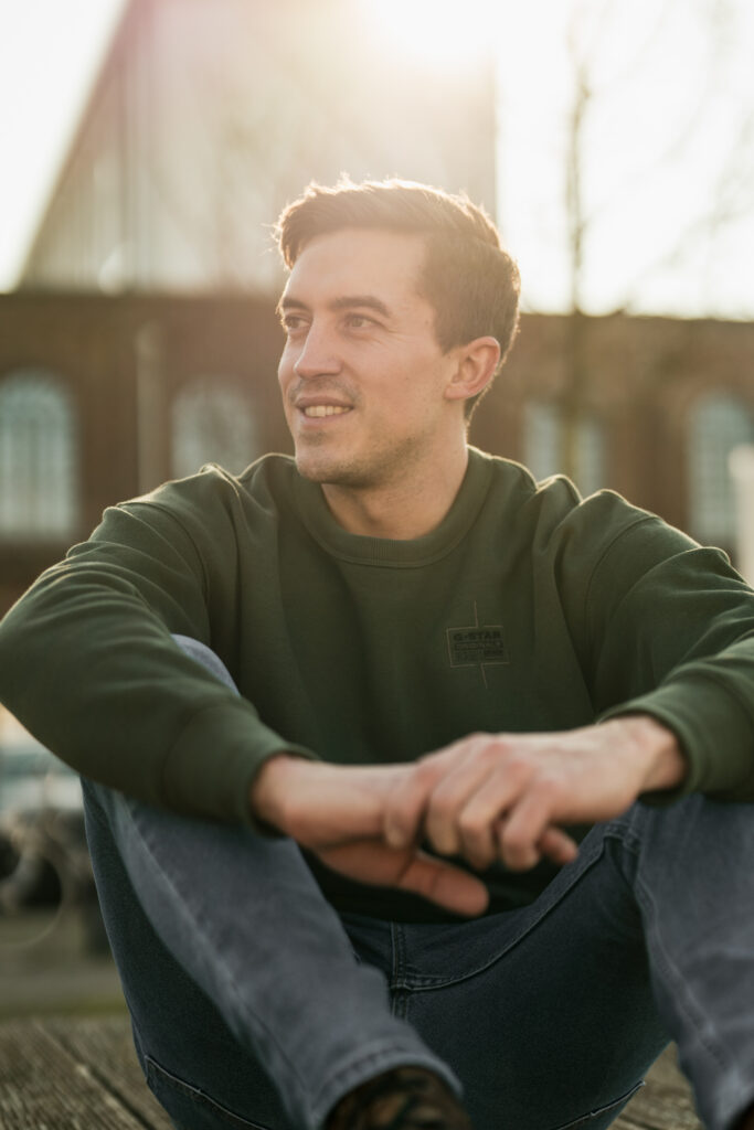 Portraitfoto eines Mannes sitzend mit Sonnenstrahlen von hinten