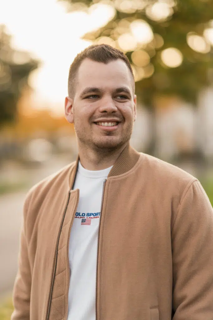 Portraitfoto eines Mannes mit freundlichem Gesichtsausdruck, bei Sonnenuntergang mit unscharfem Hintergrund