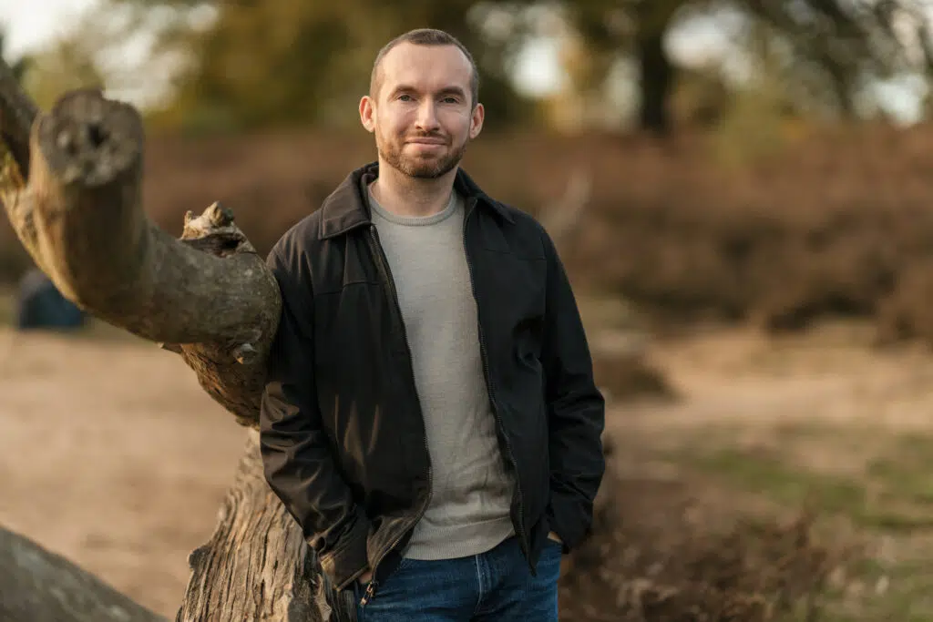 Portraitfoto eines Mannes, an einen Ast lehnend