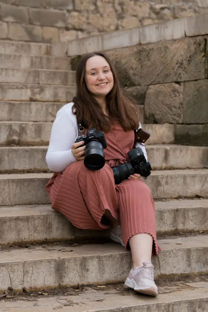 Fotografin sitzt auf einer Treppe und lächelt in die Kamera