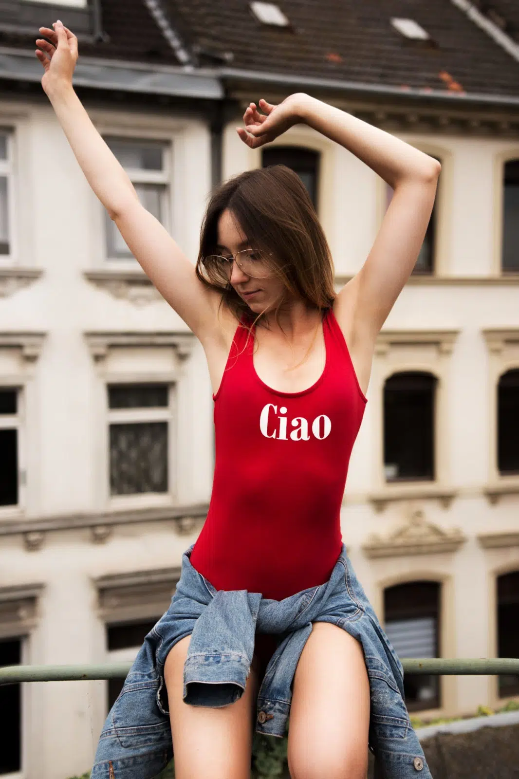 Portraitfoto einer Frau mit rotem Body, im Hintergrund eine Häuserwand