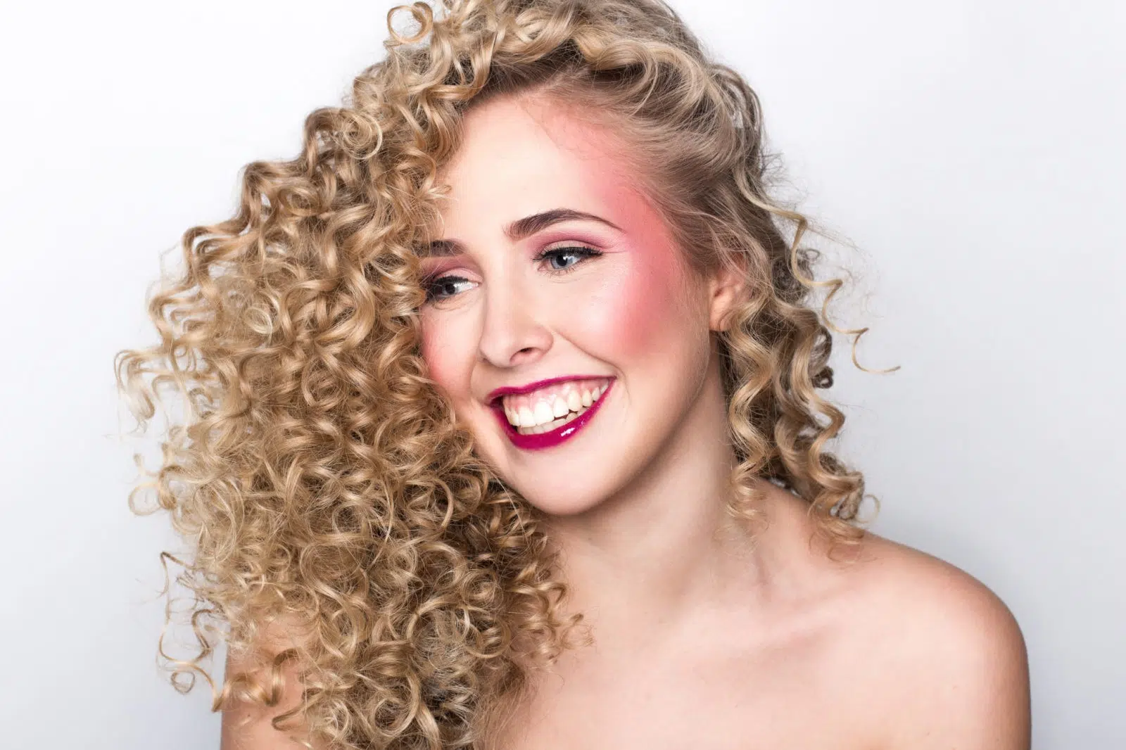 Kreatives Portraitfoto einer Frau mit lockigem Haar und starkem Make-up