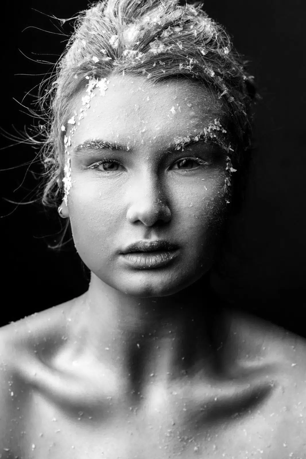 Schwarz-Weiß Portraitfoto einer Frau. Schneeflocken im Gesicht