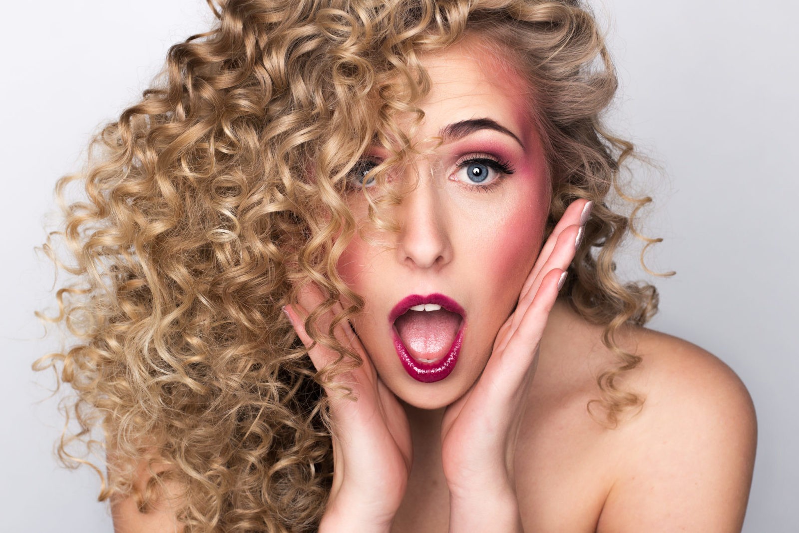Kreatives Portraitfoto einer Frau mit Locken und überraschtem Gesichtsausdruck