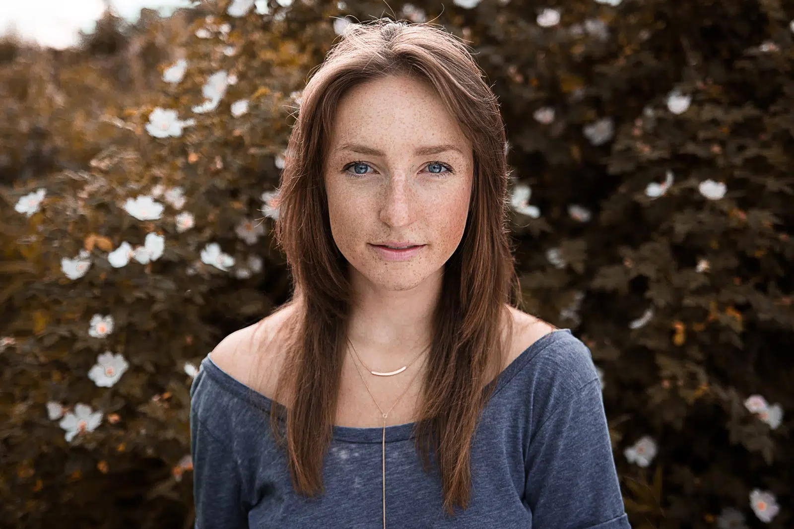 Authentisches Portraitfoto einer Frau, vor einer Hecke