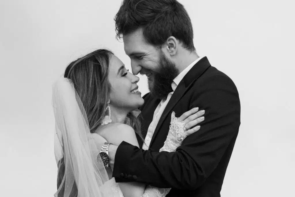 Hochzeitsportfolio, Braut und Bräutigam beim innigen Blickkontakt nah aneinandergelehnt in Schwarz Weiß