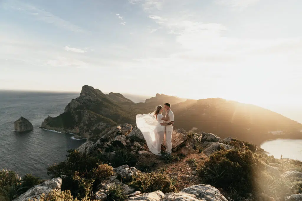 Hochzeitsportfolio, Braut und Bräutigam zusammen auf einem felsigen Gipfel mit weitem Ausblick, mit goldenem Licht der untergehenden Sonne