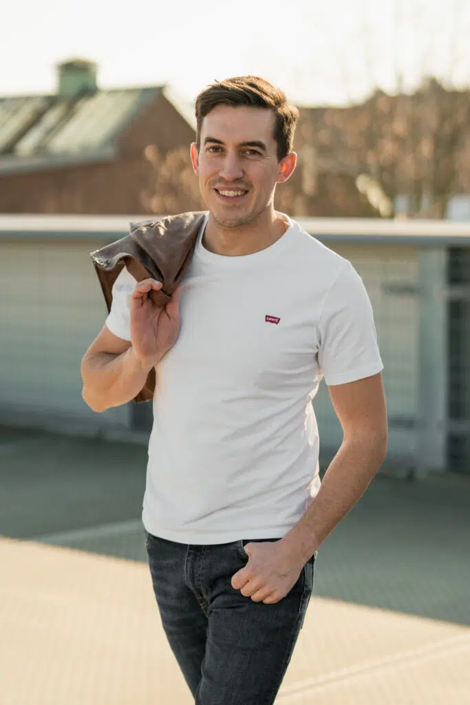 Portraitfoto eines Mannes mit Jacke über der Schulter und Sonne von hinten