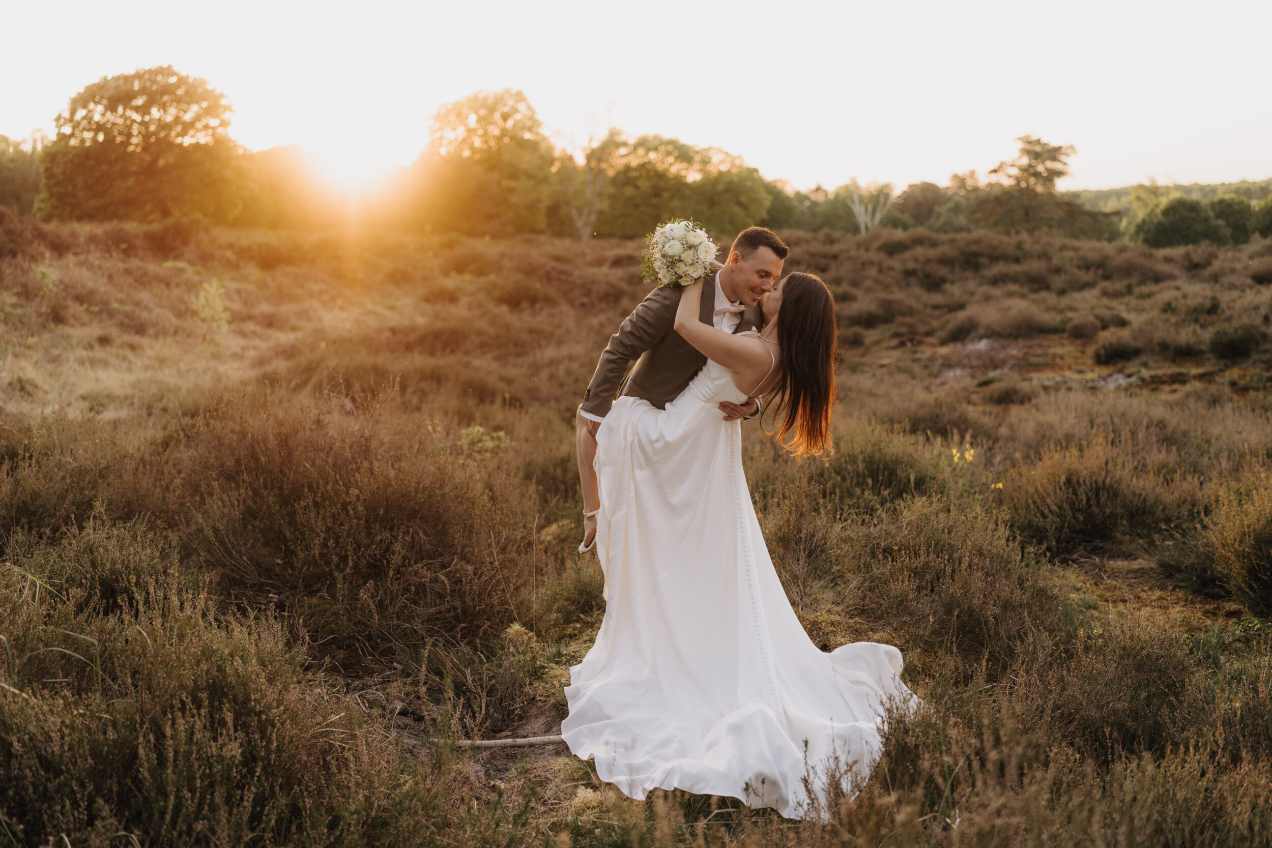 After Wedding SHooting in der Wahner Heide bei Abendlicht, ein paar steht Arm in Arm in der Wahner Heide mit Abendsonne im Hintergrund