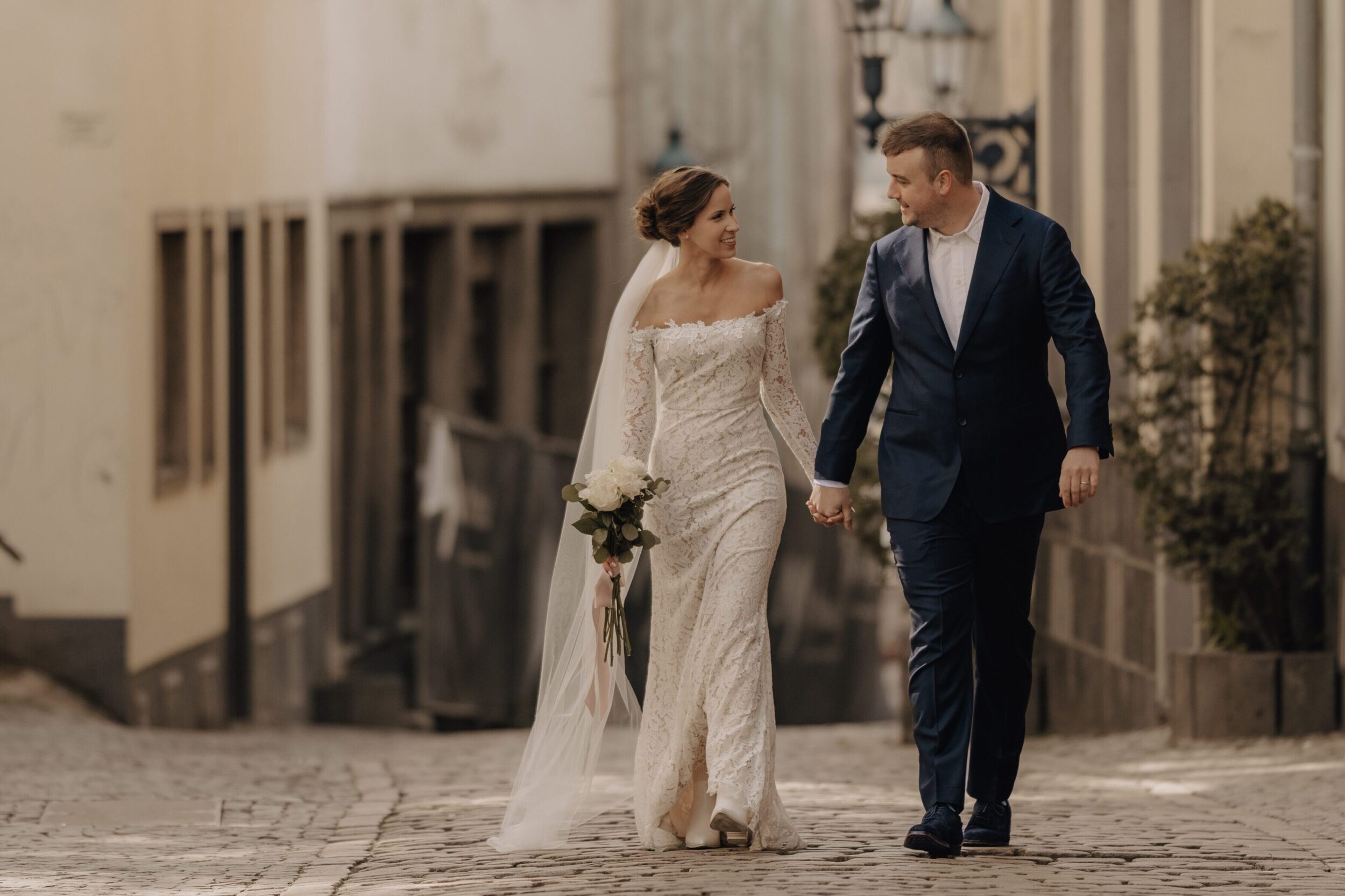 Hochzeitspaar läuft in einer Gasse auf die Fotografin zu