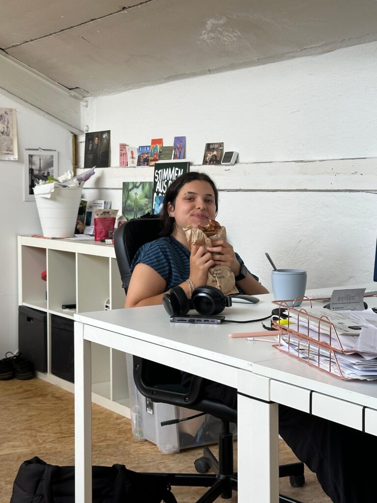 Iman beim Praktikum mit einem Franzbrötchen