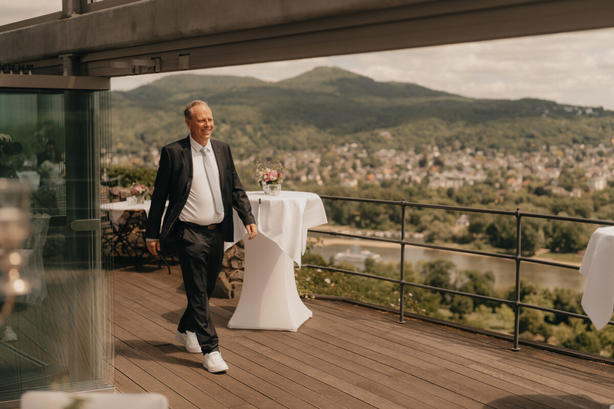 Bräutigam läuft am Restaurant Rolandsbogen auf seine Braut zu
