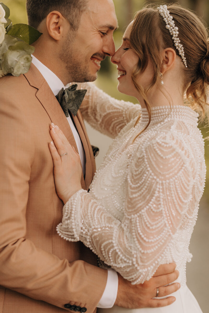 Hochzeitsportfolio, Hochzeitspaar, Braut und Bräutigam ganz nah, lachelnd, augen zu, in der rechten Hand der Blumenstrauß