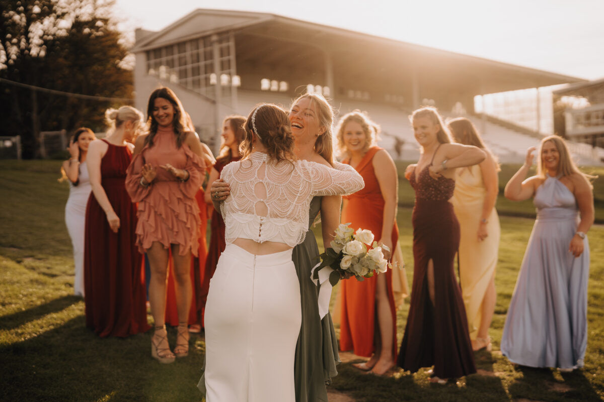 Hochzeitsportfolio, Braut und Trauzeugin umarmen sich nachdem sie den Strauß gefangen hat