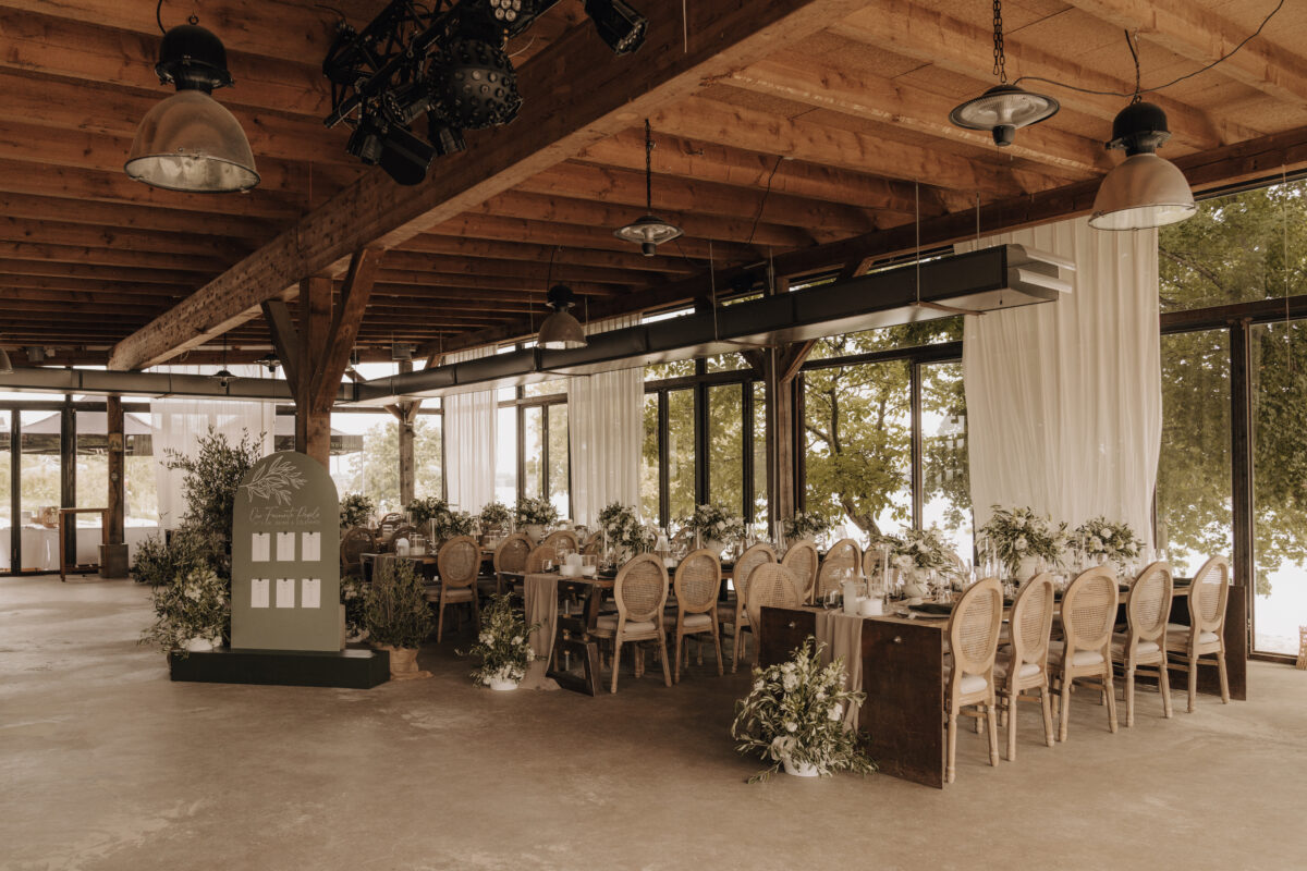 hochzeitsportfolio, rustikal dekorierte Hochzeitslocation mit langen festliche gedeckten Tischen und großen Fensterfronten