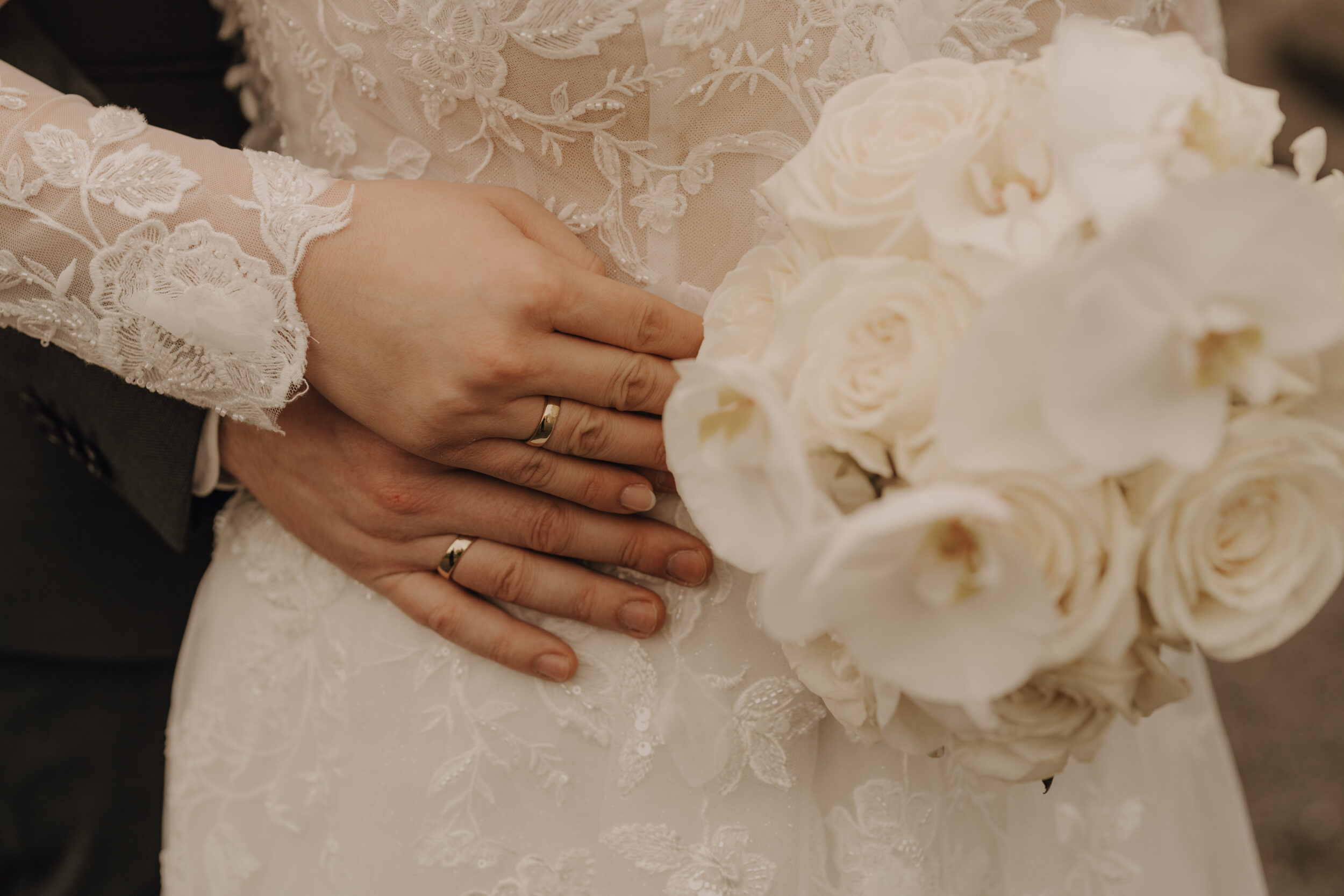 Heiraten im Rathaus Herne: Herzensmomente für die Ewigkeit Close-Up von weißem Brautstrauß mit Rosen und Orchideen, sowie den Ringen des Paares