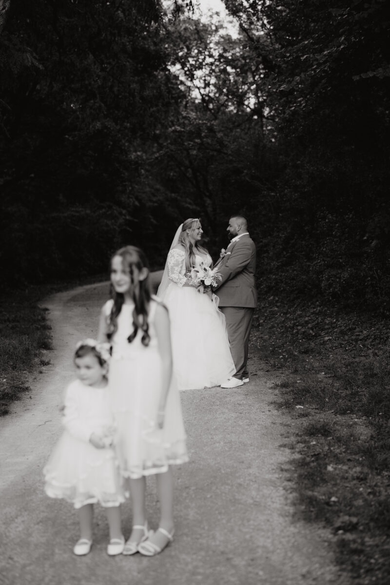 Kinder vorne, unscharf, i Hintergrund Brautpaar scharf, Hochformat schwarz-weiß