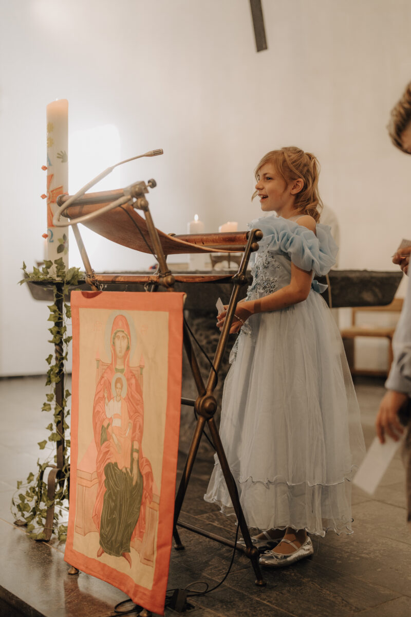 Mädchen im Hellblauen Prinzessinnen - Kleid steht am Pult und liest vor