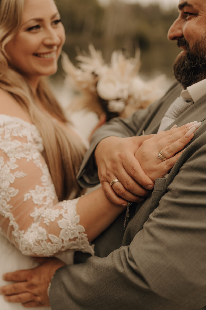 Brautpaar steht sich gegenüber und schaut sich an, die Hand der Braut liegt auf der Brust des Bräutigams, nah, warm, Hochformat