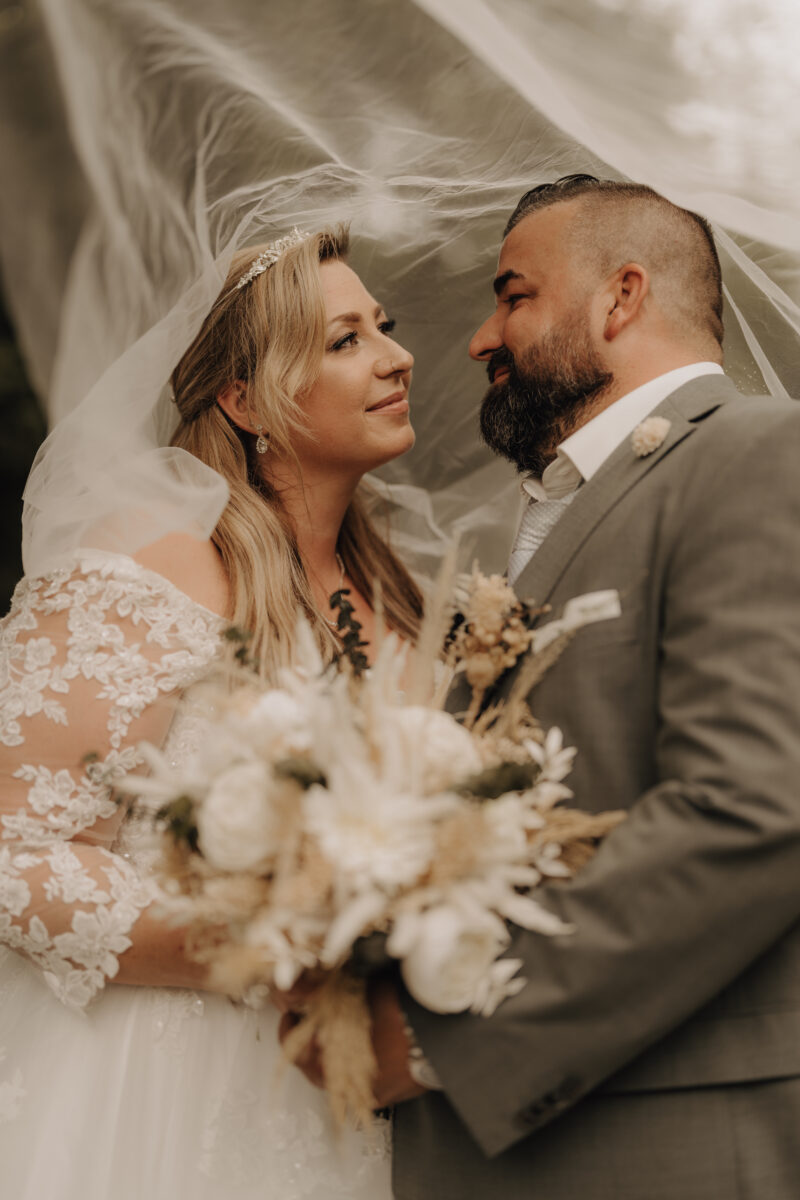 Foto Brautpaar schaut sich an 2 halbnah warm Hochformat