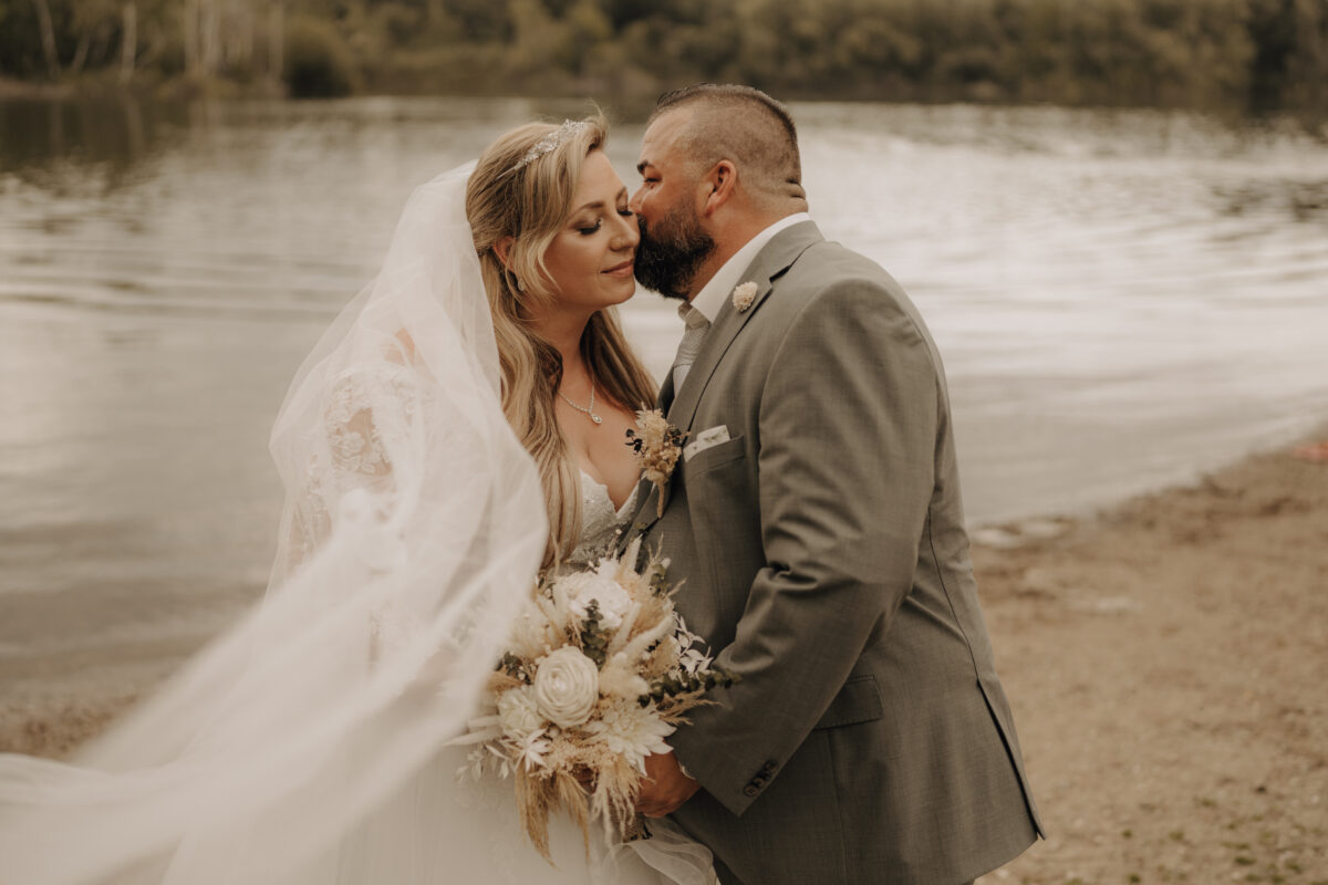 Bräutigam küsst Brait auf die linke Wange, Querformat