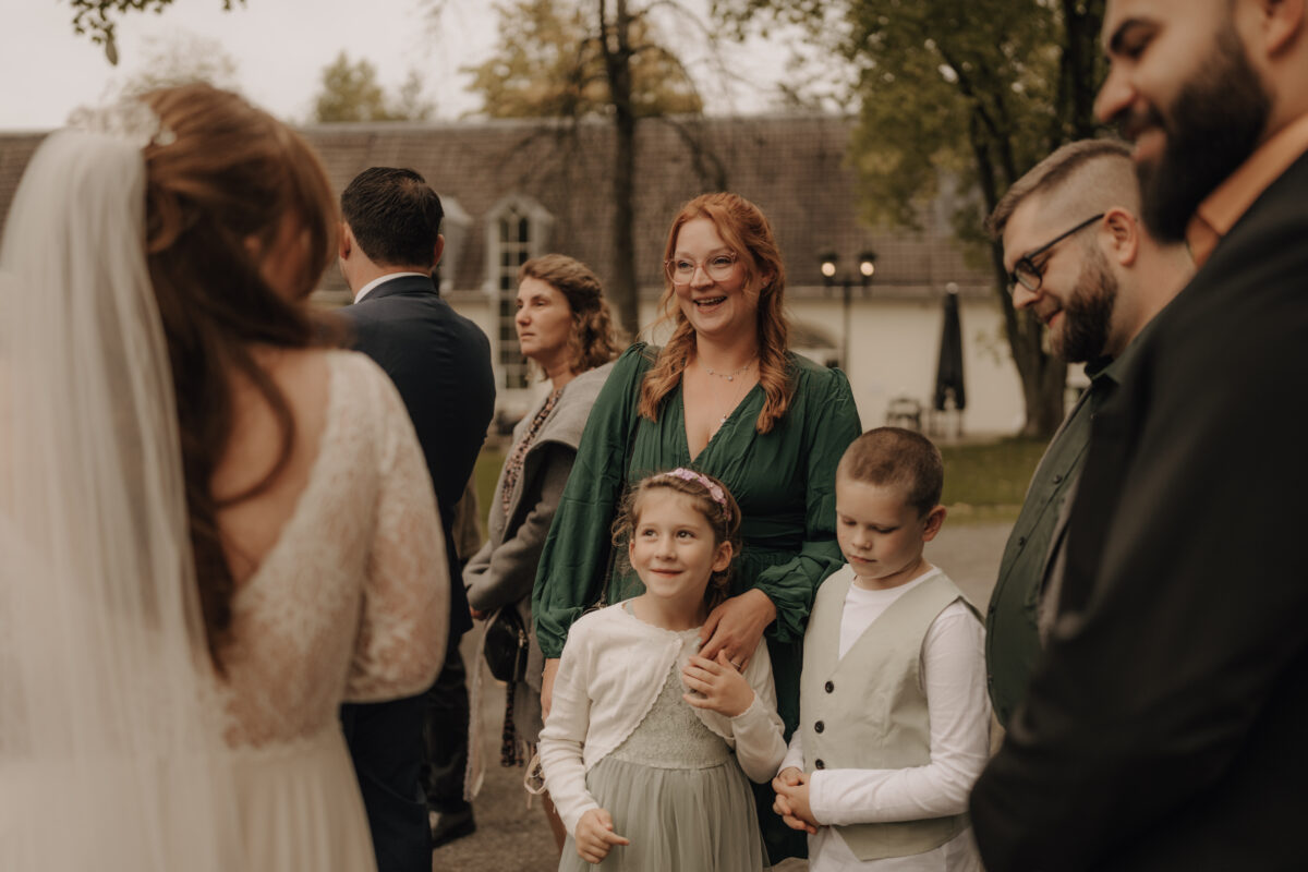 Frau im grünen Kleid mit 2 Kids unter den Gästen Foto Farbe