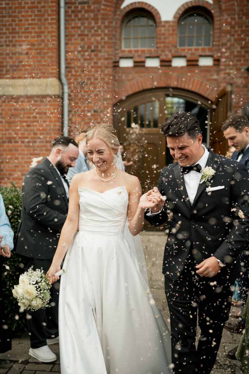 Hochzeitsportfolio, Hochzeitspaar kommen gemeinsam aus der Trauung heraus gelaufen