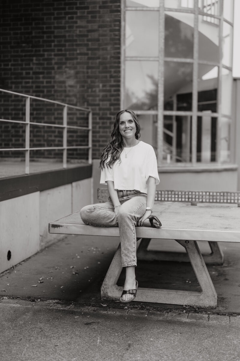 Schwarz-Weiß Portraitfoto einer Frau, sitzend auf einer Tischtennisplatte