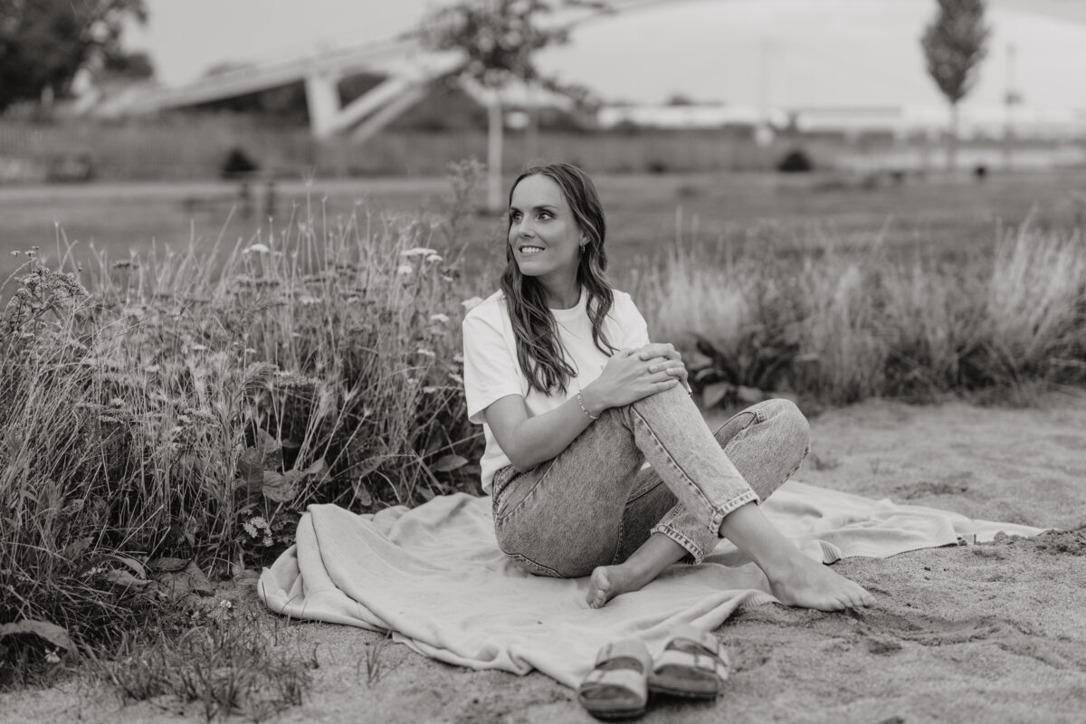 Schwarz-Weiß Portraitfoto einer Frau, auf der Wiese mit Picknickdecke sitzend