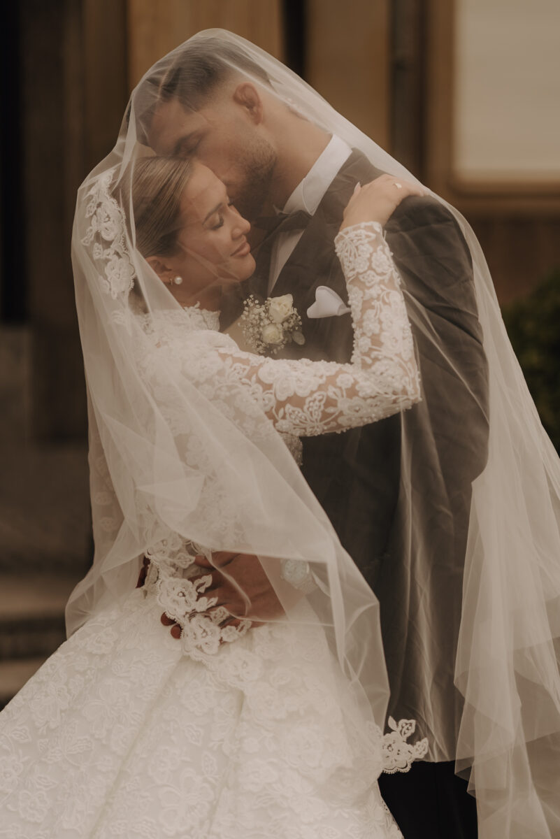 After Wedding Portfolio, Braut und Bräutigam stehen sich in den Armen haltend voreinander und sind von dem Schleier bedeckt