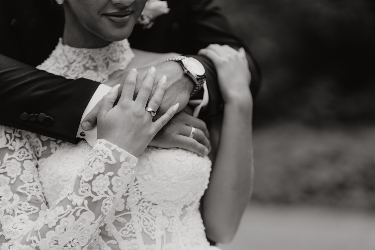After Wedding Portfolio, Detailfoto der Eheringe, Braut hält die Hände des Bräutigams, Foto in schwarz-weiß